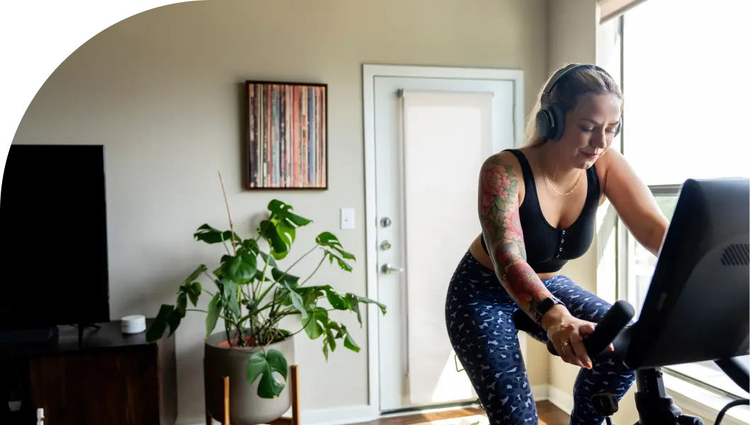 Woman exercising on a stationary bike and listening to music at her home.